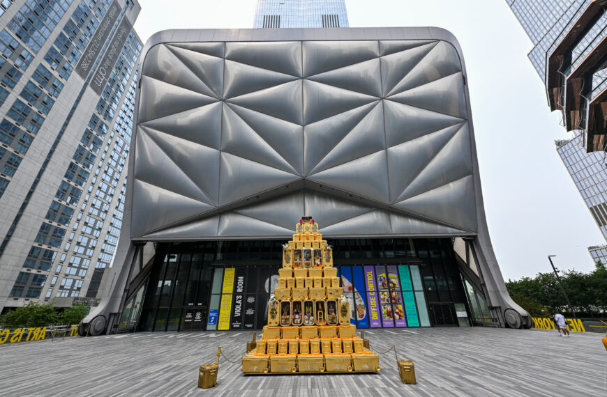 The ridged steel shell of The Shed at Hudson Yards, with a tiered gold sculpture standing on the plaza in front of the entrance
