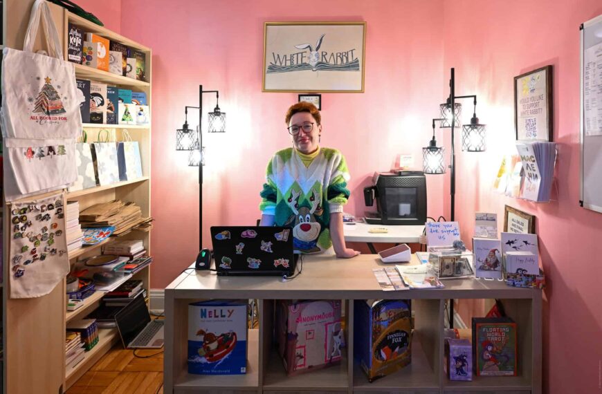 Person at NYC map-themed merchandise store counter with books and souvenirs.