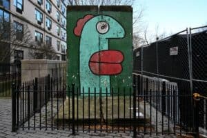 Colorful graffiti mural of a cartoonish face on a city wall in NYC.