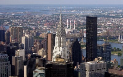 The stainless-steel crown and spire of the Chrysler Building rising above Midtown, with the East River behind