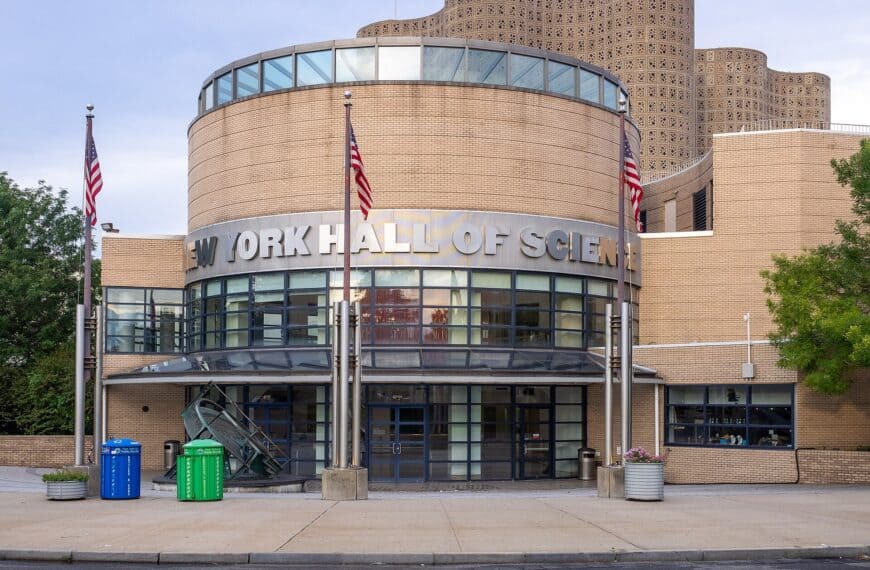 The curved brick facade of the New York Hall of Science in Flushing Meadows, flags standing before the entrance