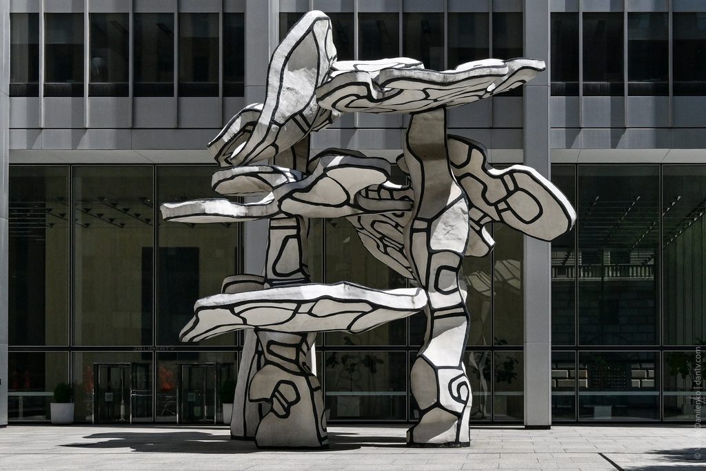 Group of Four Trees straight on, its trunks and flat canopies set against the glass facade behind