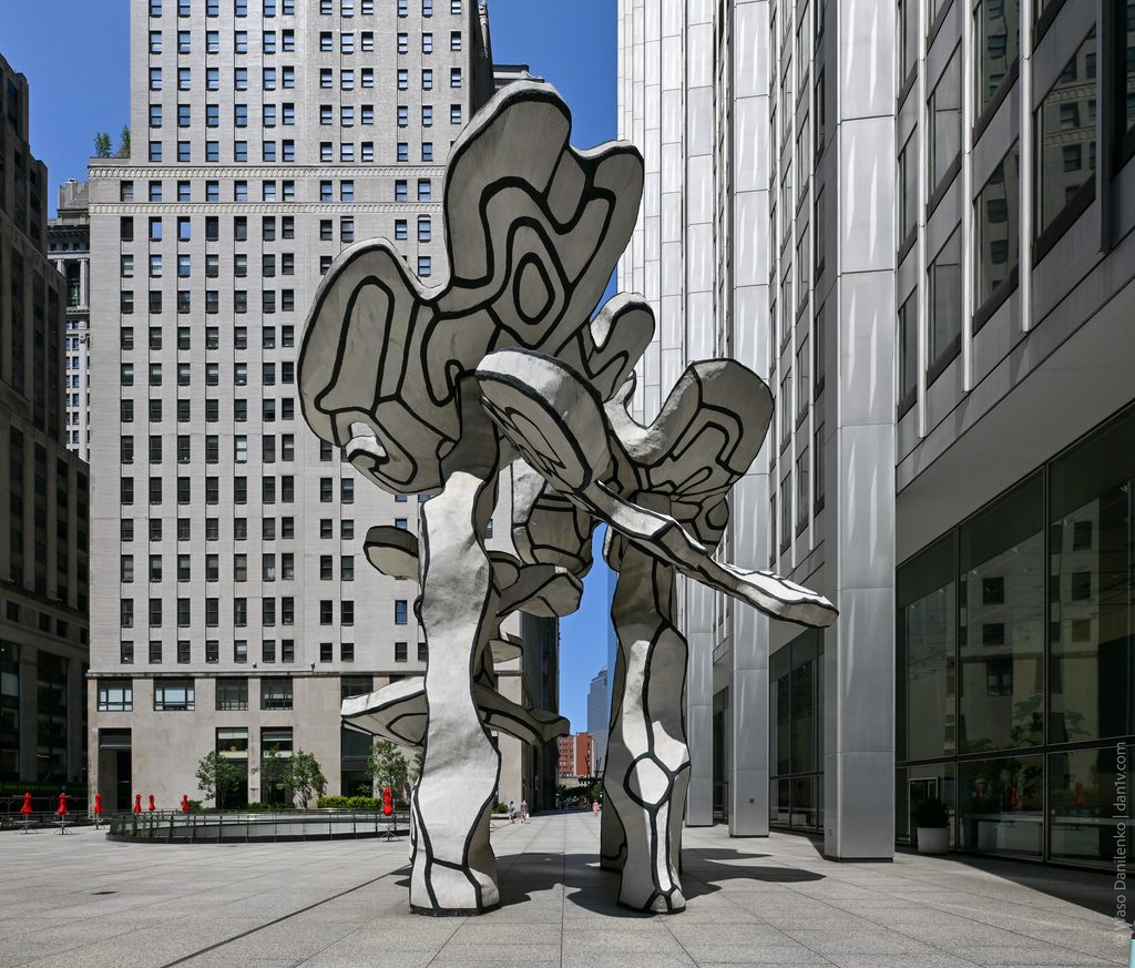 The full height of Group of Four Trees on the plaza at 28 Liberty Street, framed by the surrounding skyscrapers
